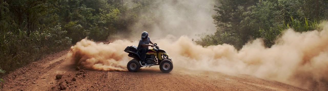 Quad ATV na szutrowej drodze w lesie, spod kół unosi się pył